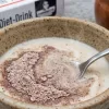 Mixing ragi milk powder into warm milk for a healthy diet.